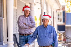 two men smiling with Santa hats
